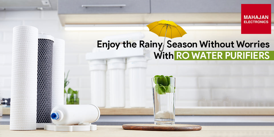 RO filter cartridges and a glass of water with mint on a kitchen counter, a yellow umbrella and the words Enjoy the Rainy Season Without Worries With RO Water Purifiers beside the Mahajan Electronics logo