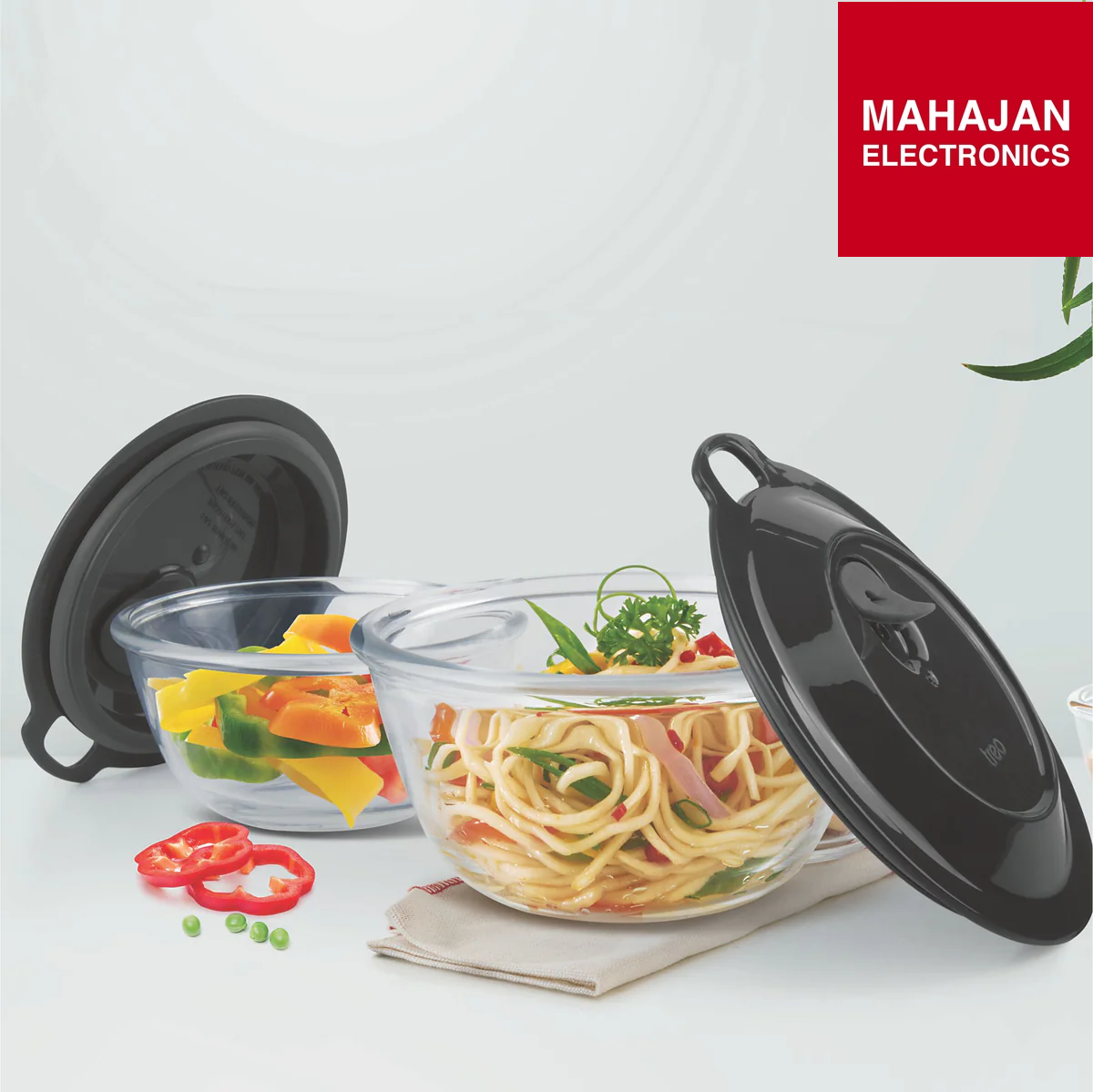 Glass bowls with black lids containing food on a white background, featuring the Mahajan Electronics logo.